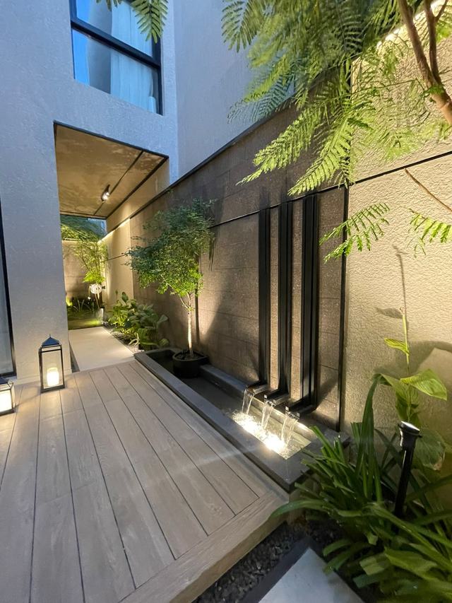 Side garden with a water wall and decking
